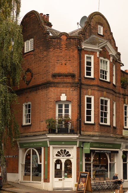 A quiet residential street in Hampstead featuring narrow asphalt road with yellow lines along the edges, flanked by historic dark brick townhouses on the left with white-framed windows, and a paved si